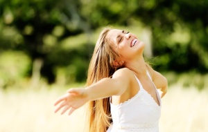 Woman outside in the sun with her arms held wide - happy.